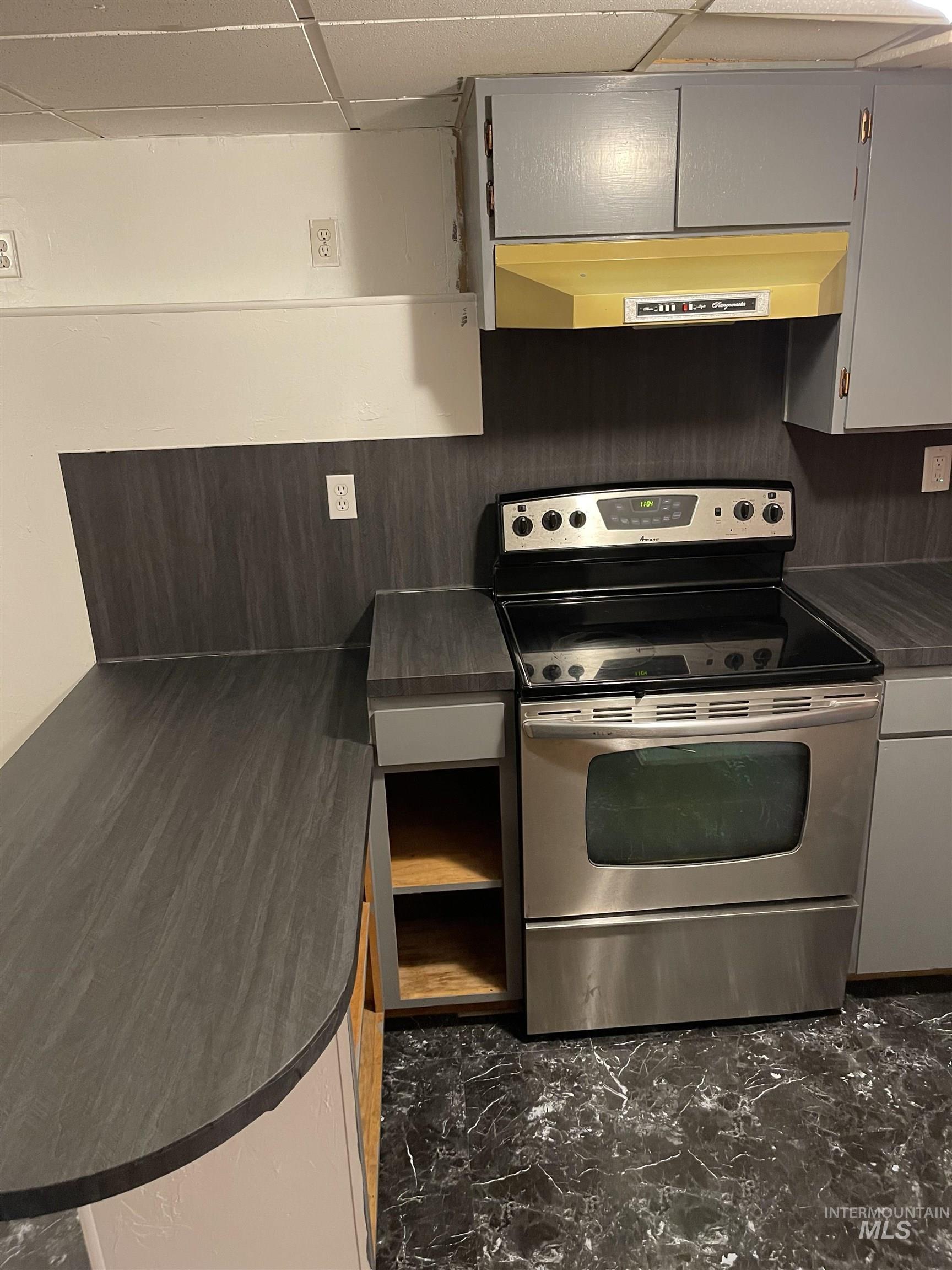 242 8th Avenue East Twin Falls, ID 83301 - Photo 29 of 39 Kitchen featuring dark countertops, stainless steel range with electric stovetop, under cabinet range hood, and a peninsula