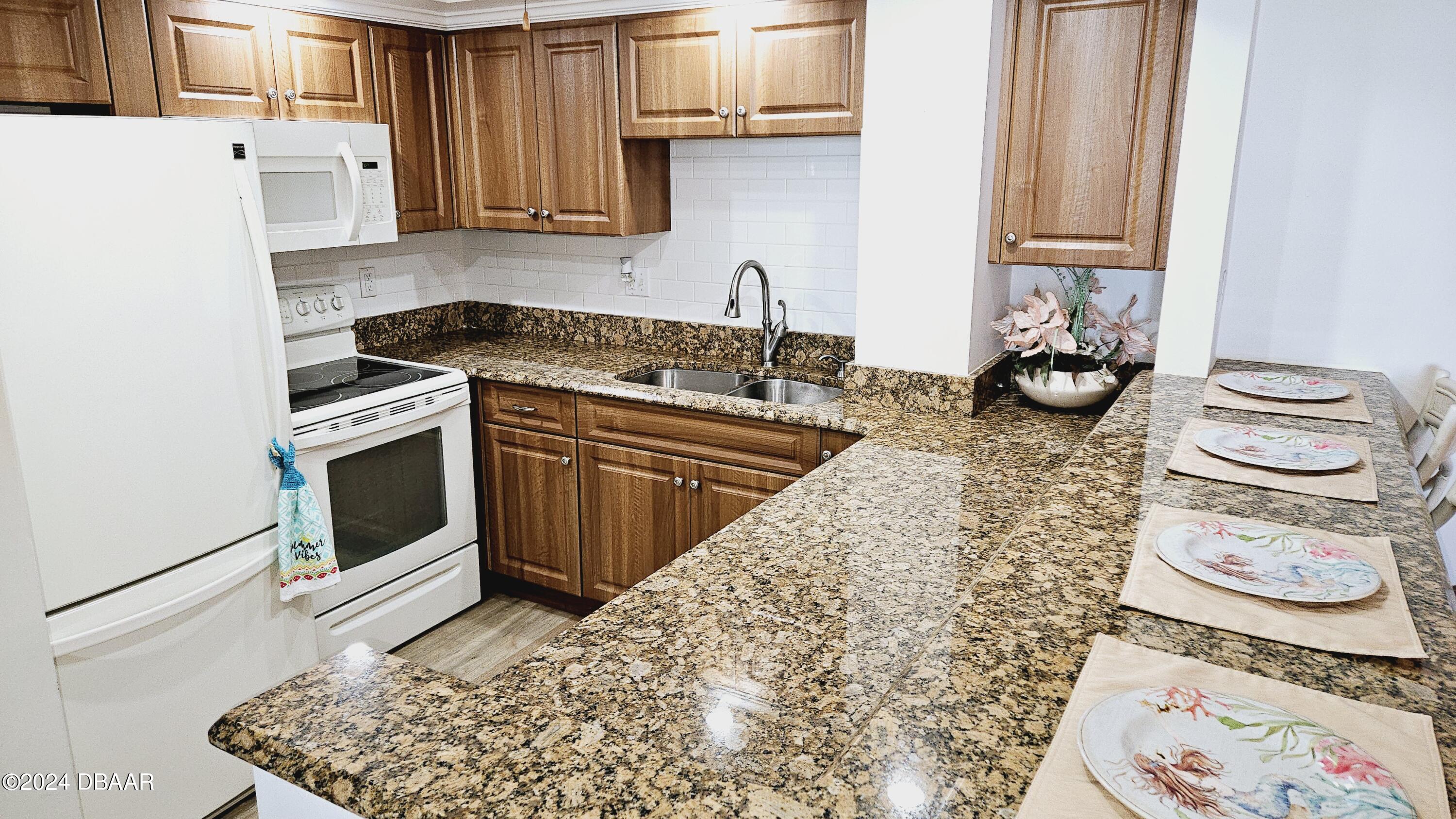 1575 Ocean Shore Boulevard, Unit 1003 Ormond Beach, FL 32176 - Photo 10 of 40 a kitchen with stainless steel appliances granite countertop a stove and a sink