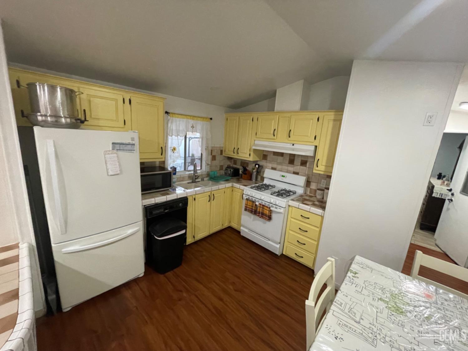 Undisclosed Address Bakersfield, CA 93304 - Photo 10 of 24 a kitchen with a refrigerator a sink dishwasher and a stove with wooden floor