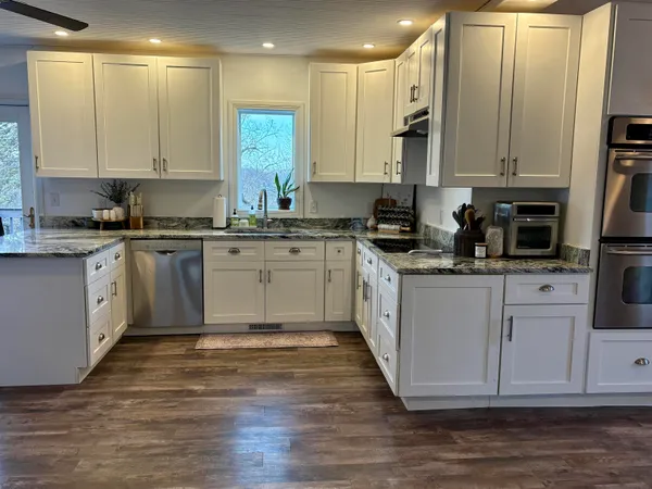 a kitchen with stainless steel appliances granite countertop a stove a sink and white cabinets