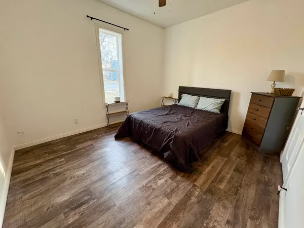 a spacious bedroom with a bed and wooden floor