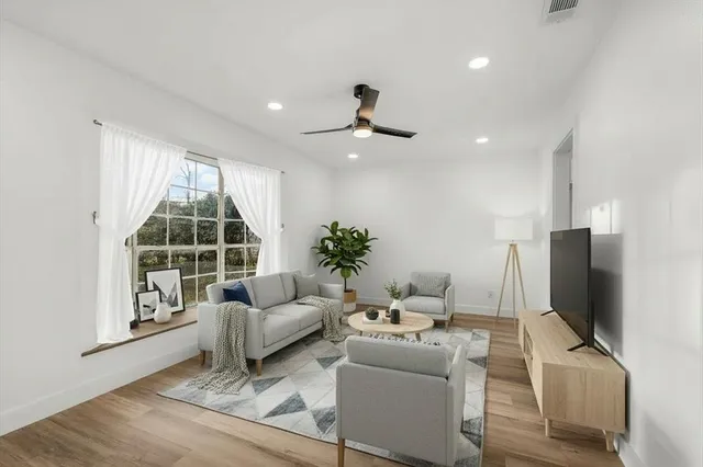 a living room with furniture a ceiling fan and a flat screen tv