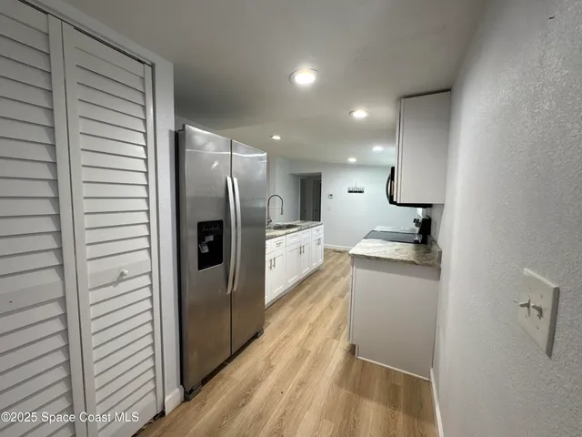 a view of kitchen with kitchen island white cabinets and refrigerator
