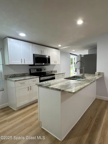 a kitchen with stainless steel appliances granite countertop a sink a stove and a microwave