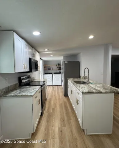 a large kitchen with stainless steel appliances granite countertop a stove and a sink