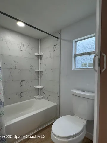 a white toilet sitting next to a bath tub and a shower