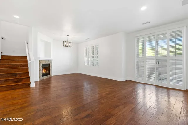 an empty room with wooden floor fireplace and windows