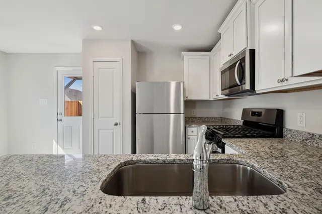 a kitchen with stainless steel appliances granite countertop a sink a stove and a refrigerator