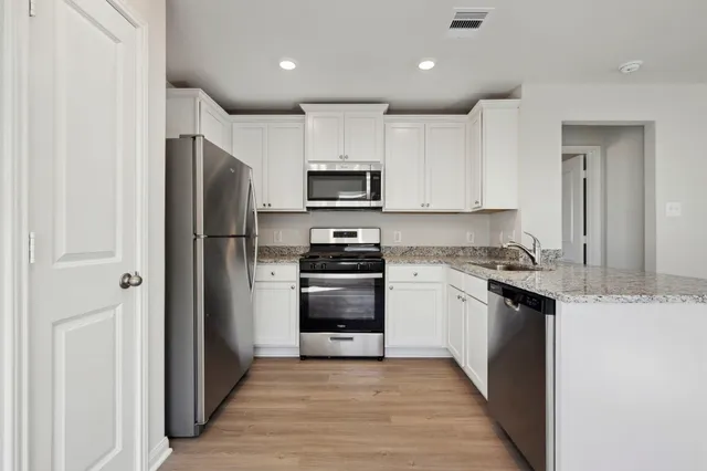 a kitchen with granite countertop a refrigerator and a stove top oven