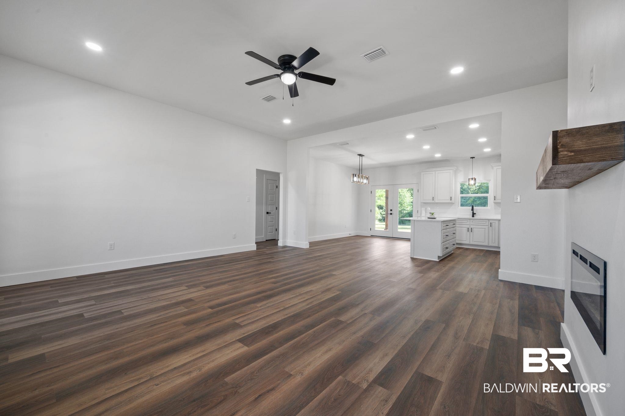 12100 Lott Road Chunchula, AL 36521 - Photo 2 of 21 Unfurnished living room with sink, french doors, ceiling fan with notable chandelier, and wood-type flooring