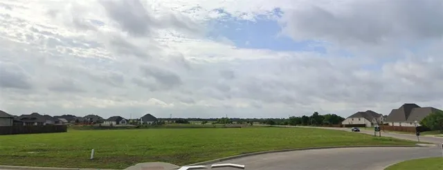 a view of a city with green space and wooden fence