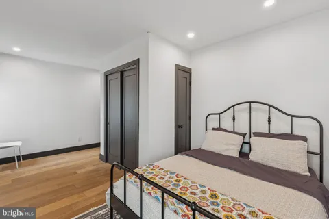 a bedroom with a bed a window with wooden floor
