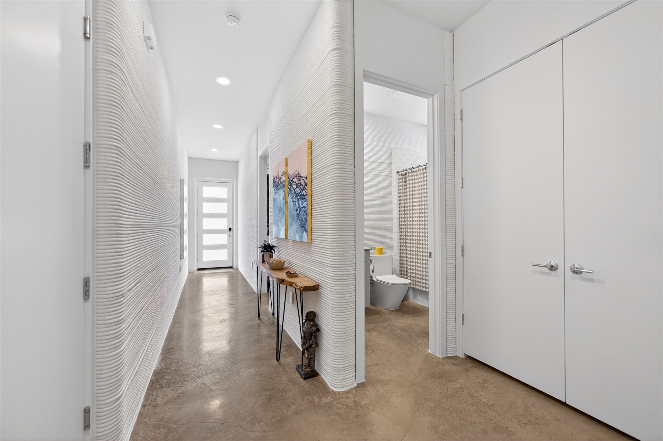 308 Painted Sunset Drive Georgetown, TX 78628 - Photo 17 of 26 Hallway featuring textured white walls, recessed lighting, polished concrete flooring, white interior doors, and a front entry door with frosted glass panels