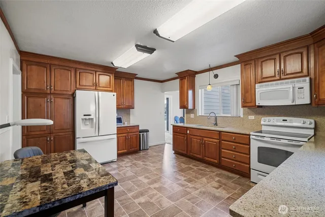 a kitchen with granite countertop a sink stove and refrigerator