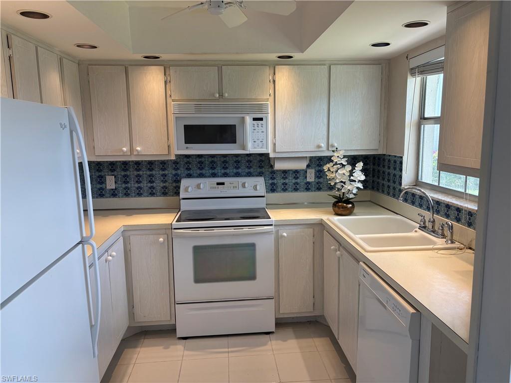 315 St Andrews Boulevard, Unit A2 Naples, FL 34113 - Photo 11 of 17 Kitchen featuring white appliances, light countertops, light tile patterned floors, and ceiling fan