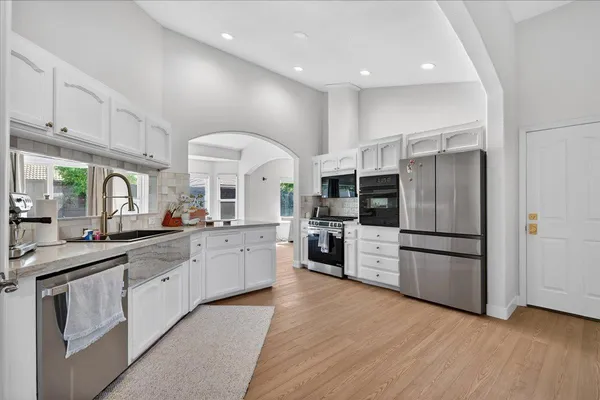 a dining room with furniture wooden floor a rug and a kitchen view
