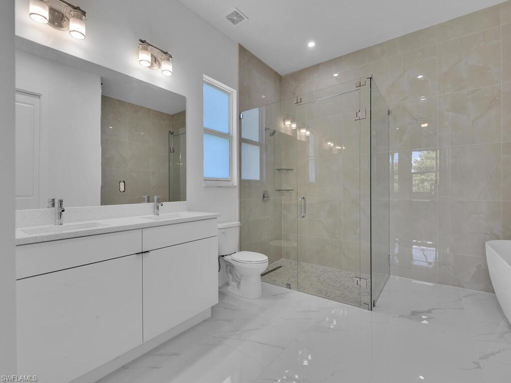 6108 Stratton Road Fort Myers, FL 33905 - Photo 15 of 27 Bathroom with a shower stall, a soaking tub, double vanity, and marble finish flooring
