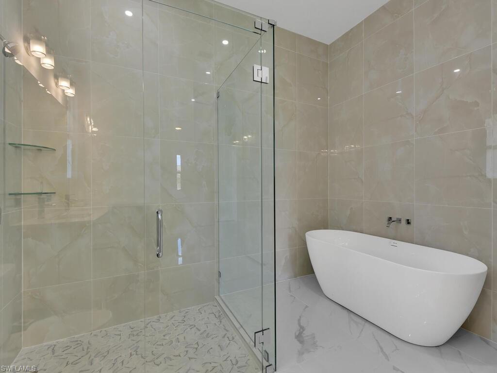 6108 Stratton Road Fort Myers, FL 33905 - Photo 16 of 27 Bathroom featuring a freestanding bath, a shower stall, marble tiled flooring, and tile walls