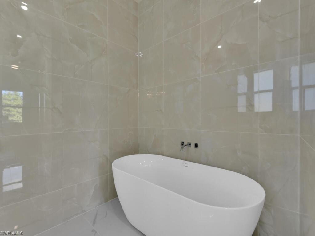 6108 Stratton Road Fort Myers, FL 33905 - Photo 17 of 27 Bathroom with tile walls, a freestanding tub, and marble finish flooring