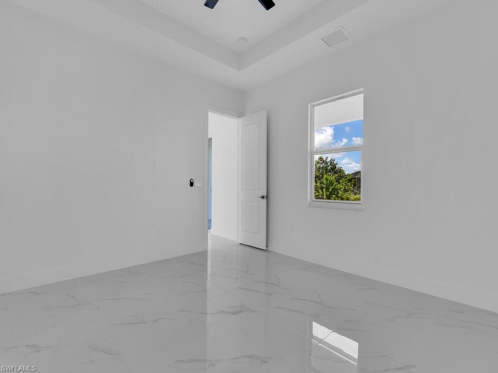 6108 Stratton Road Fort Myers, FL 33905 - Photo 25 of 27 Empty room with marble finish floors, a ceiling fan, and a tray ceiling