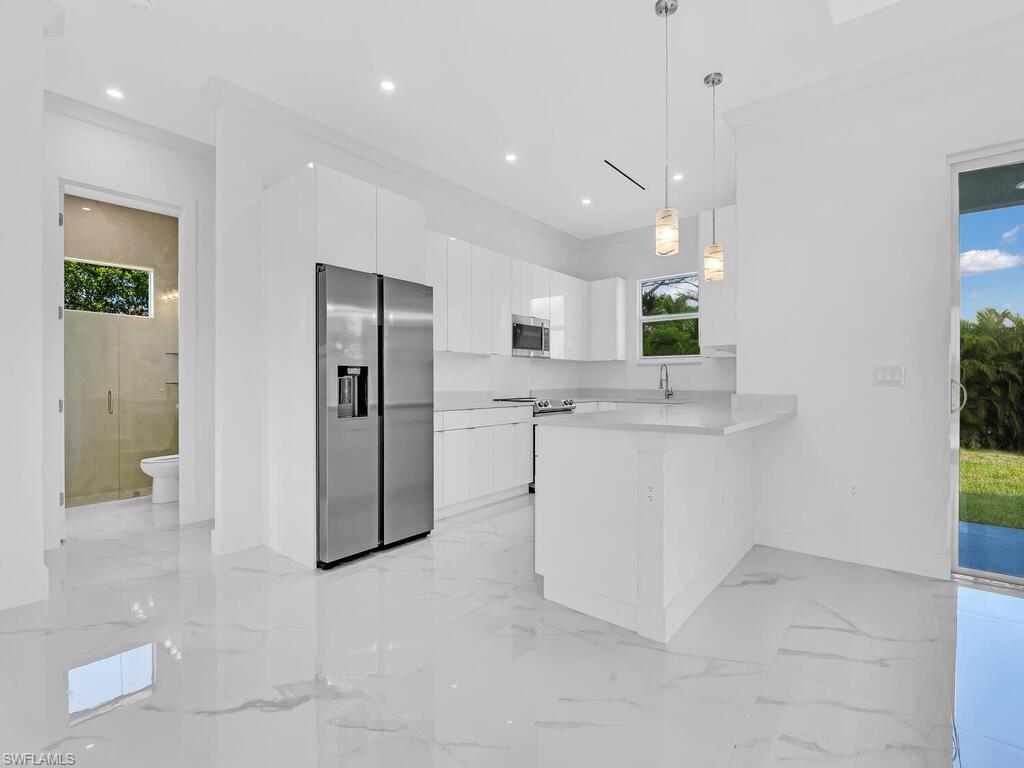 6108 Stratton Road Fort Myers, FL 33905 - Photo 7 of 27 Kitchen with stainless steel appliances, a peninsula, white cabinets, modern cabinets, and light countertops