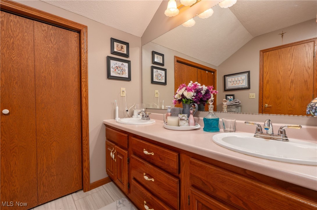 6535 Middle Run Road Dover, OH 44622 - Photo 18 of 40 Full bath with lofted ceiling, double vanity, and a textured ceiling