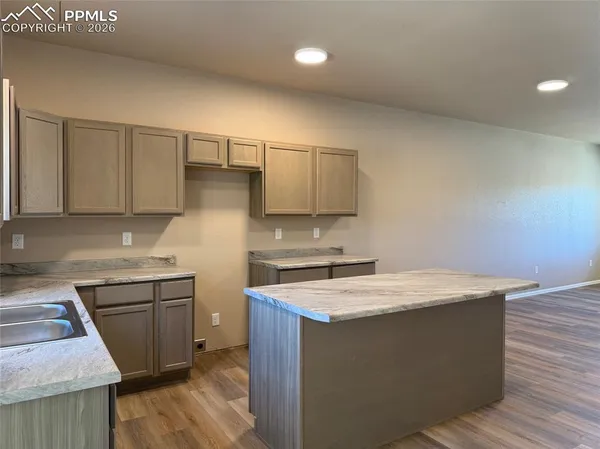 a kitchen with granite countertop white cabinets and wooden floor
