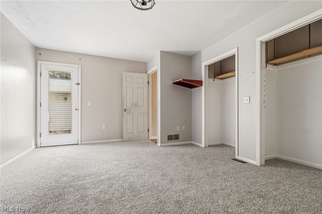 4449 18th Street Northwest Canton, OH 44708 - Photo 13 of 25 Spacious room featuring light gray wall paint, textured light gray carpeting, and a white ceiling with a decorative light fixture