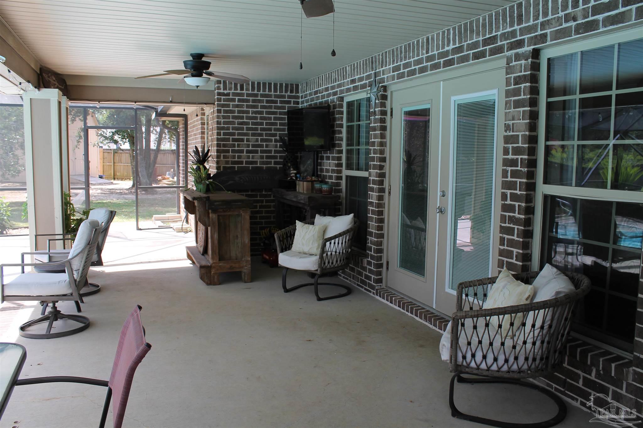 5468 Madelines Way Pace, FL 32571 - Photo 12 of 45 a living room with furniture a flat screen tv and a floor to ceiling window