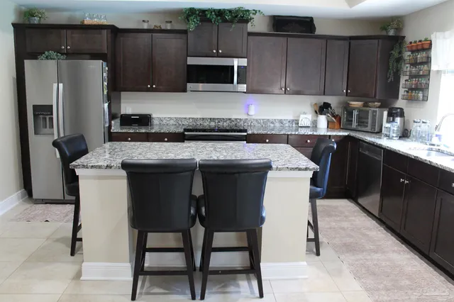 a kitchen with stainless steel appliances kitchen island granite countertop a table chairs microwave and sink