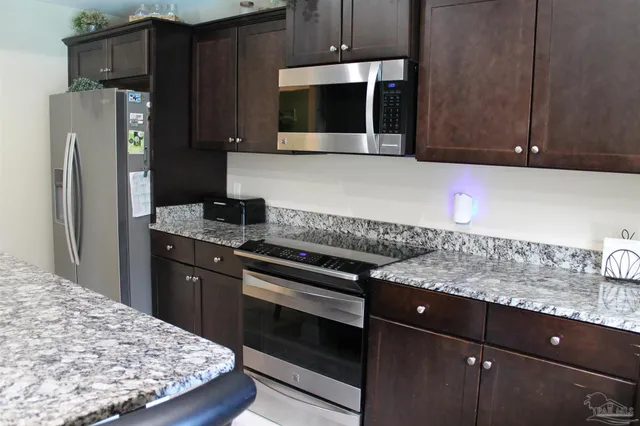 a kitchen with granite countertop wooden cabinets and stainless steel appliances