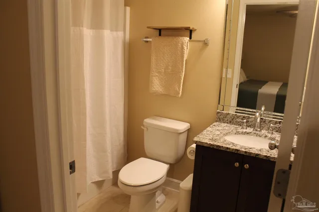 a bathroom with a granite countertop sink toilet and mirror