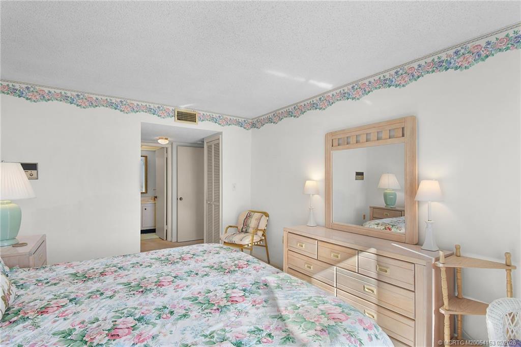5413 Southeast Miles Grant Road, Unit G206 Stuart, FL 34997 - Photo 16 of 79 a bedroom with a bed and a mirror on dresser