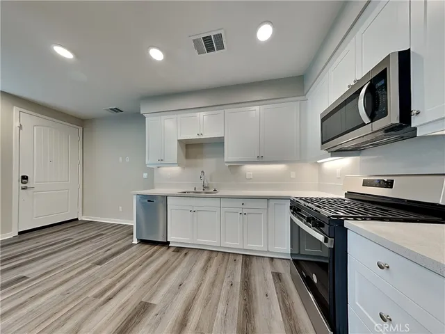 a kitchen with granite countertop cabinets stainless steel appliances and a wooden floor