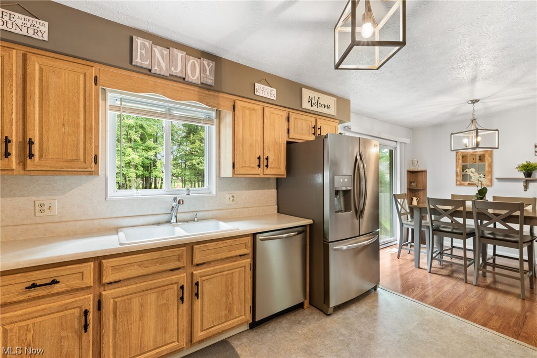 9935 Fair Road Strongsville, OH 44149 - Photo 11 of 34 Kitchen featuring a textured ceiling, brown cabinets, light countertops, appliances with stainless steel finishes, and light hardwood flooring