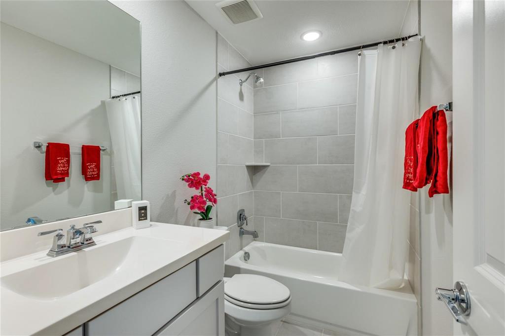 1309 Old Rocksprings Pass Mansfield, TX 76063 - Photo 23 of 36 Bathroom featuring a single vanity with an undermount sink, a large wall-mounted mirror, and a tiled tub-shower combination with a built-in shelf