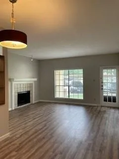 a view of an empty room with window and wooden floor