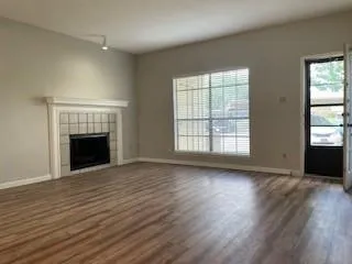 an empty room with wooden floor fireplace and windows