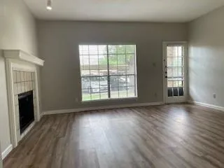 an empty room with wooden floor fireplace and windows