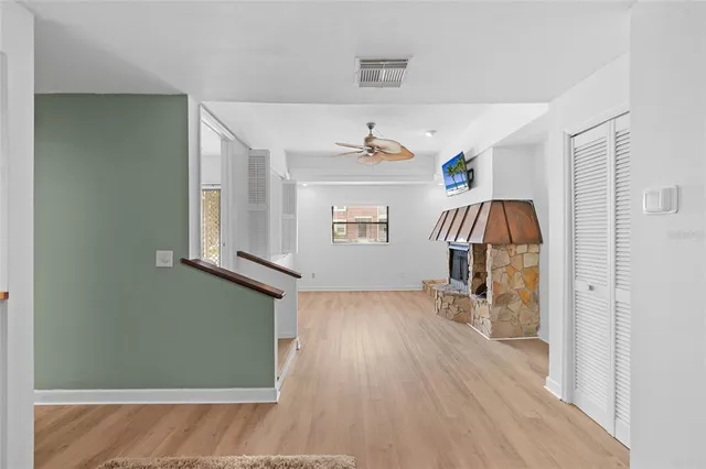 a view of empty room with wooden floor and fan