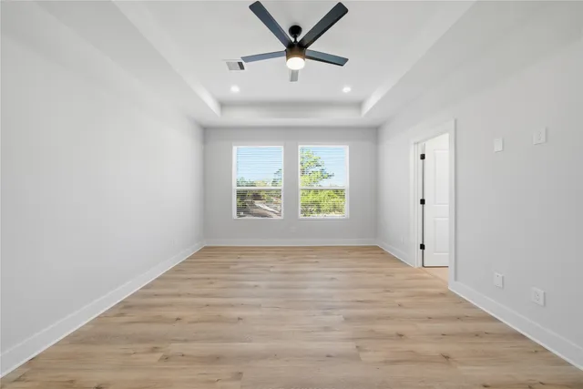 a view of an empty room with a window and wooden floor