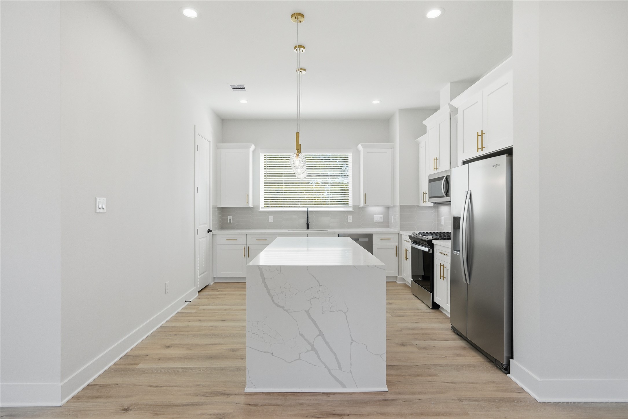 10929 Ivyridge Road, Unit B Houston, TX 77043 - Photo 30 of 37 a large kitchen with a center island wooden floor and stainless steel appliances