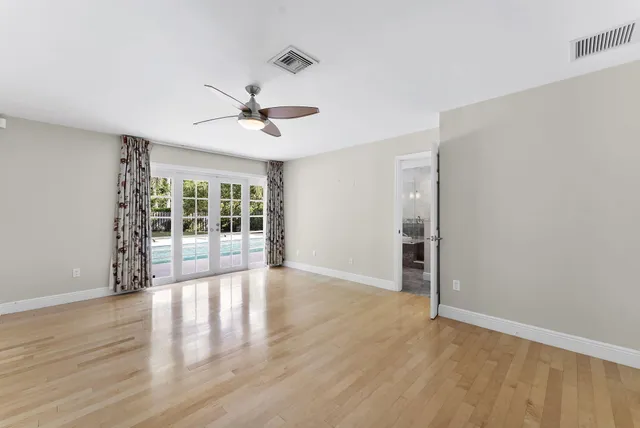 a view of an empty room with a window and wooden floor