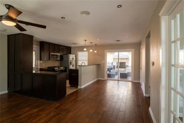 a kitchen with stainless steel appliances kitchen island granite countertop a refrigerator a stove a sink and a oven with wooden floor