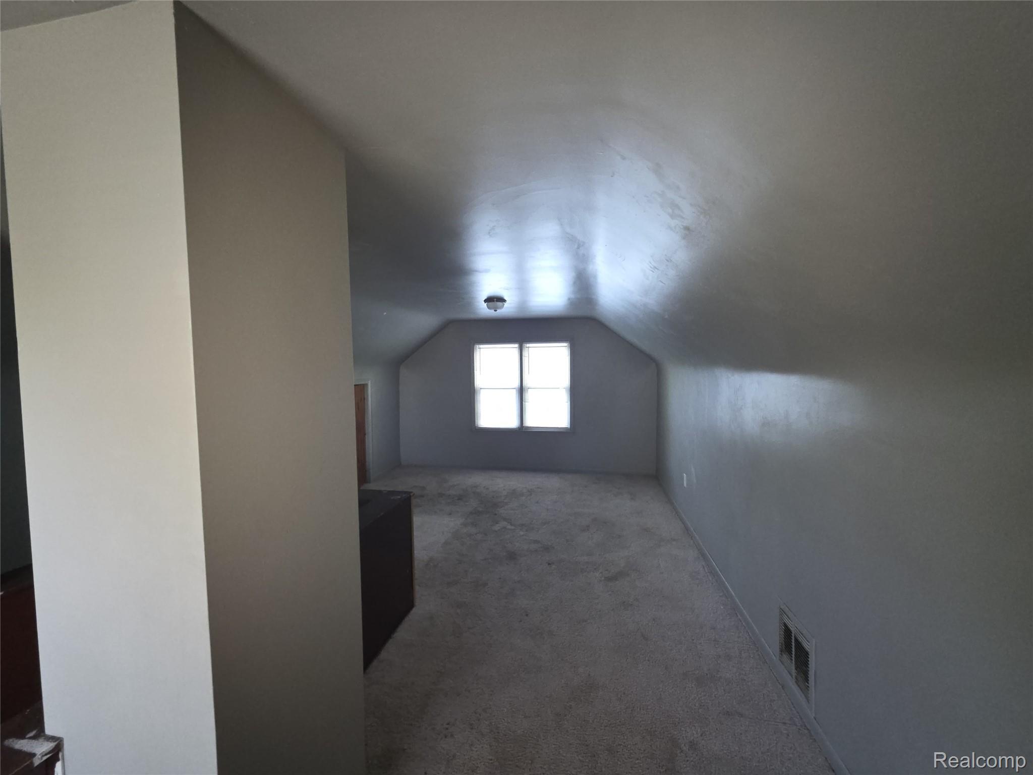 9025 Burt Road Detroit, MI 48228 - Photo 11 of 12 Carpeted room featuring sloped ceilings, a centered window, and a flush-mount ceiling light
