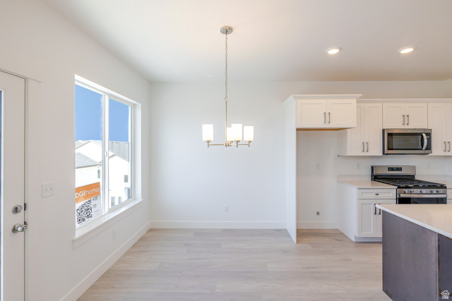 4720 Heartwood Road, Unit 438 Mapleton, UT 84664 - Photo 6 of 19 Kitchen with stainless steel appliances, light wood finished floors, a chandelier, two tone color scheme, and light stone countertops