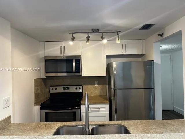 a kitchen with stainless steel appliances granite countertop a refrigerator and a stove top oven