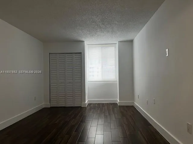 an empty room with wooden floor and window