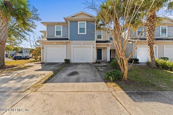 a view of a white house with a large tree