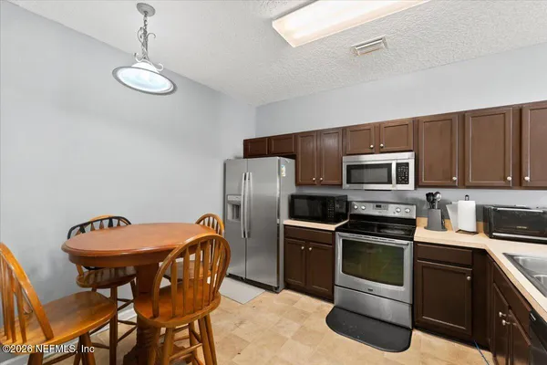 a kitchen with stainless steel appliances granite countertop a sink a stove a refrigerator cabinets and chairs